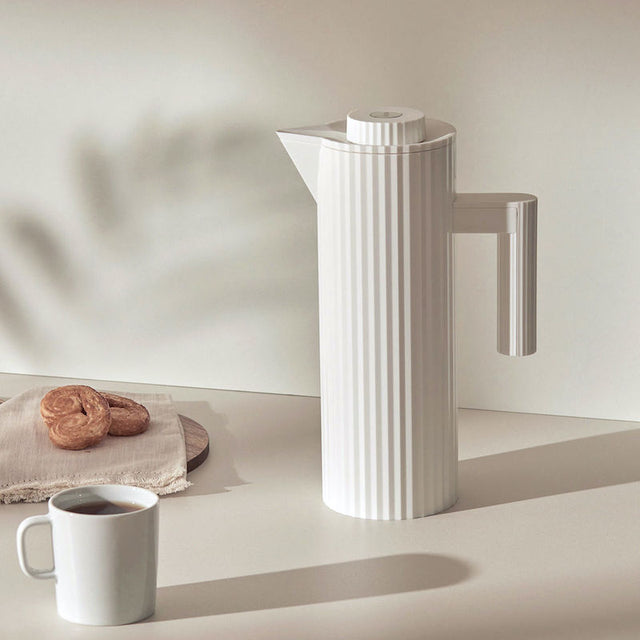 Alessi Plissé Thermoskanne in Weiß mit Tasse auf dem Tisch